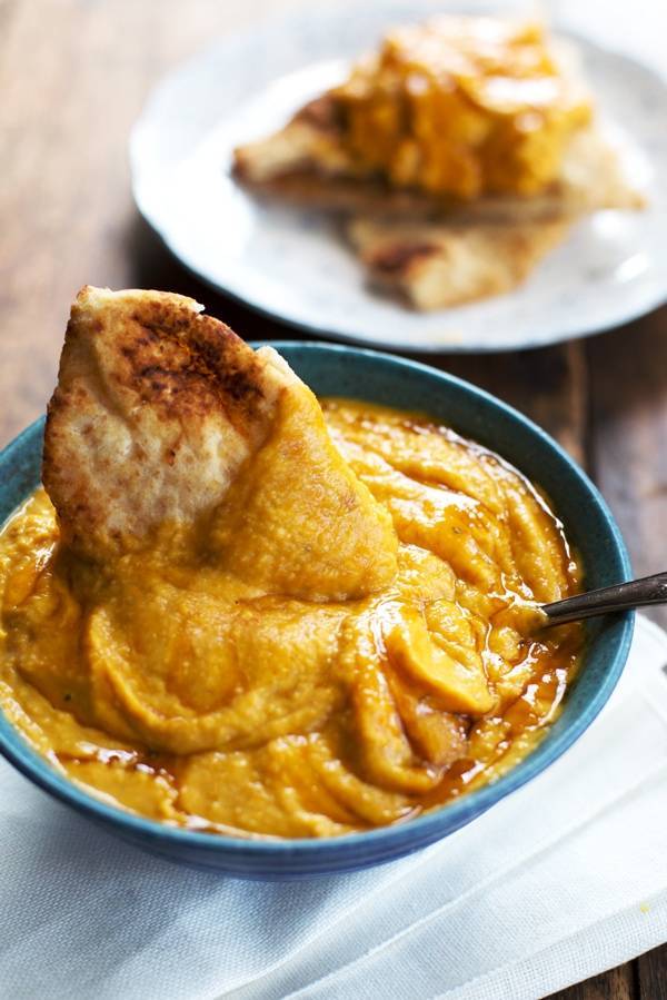 Hummus on a pita chip in a blue bowl.