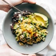 Migas in a bowl with avocado and refried black beans.