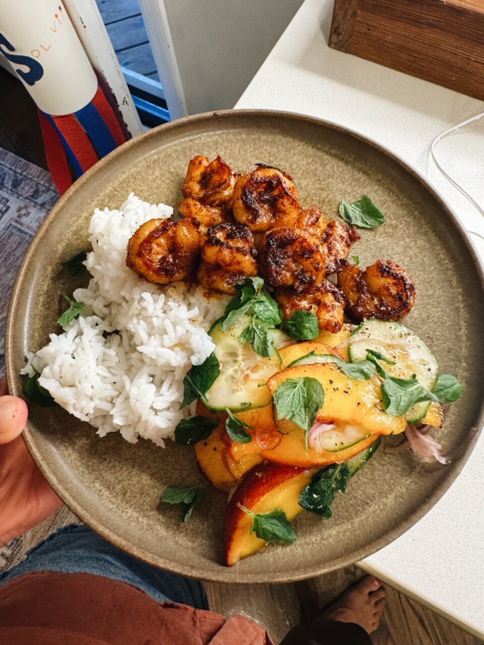 Peach salad on a plate with shrimp and rice.